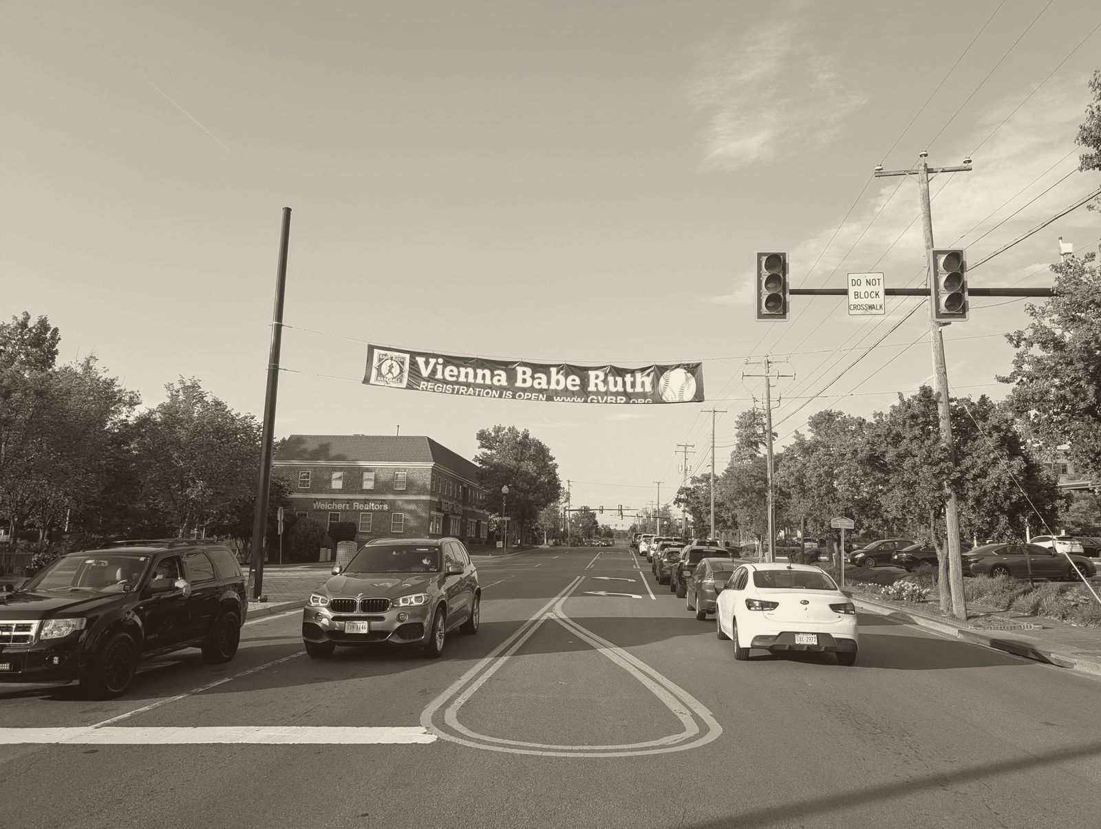 Cars queued at a light on Maple Avenue beneath a Vienna Babe Ruth baseball banner
