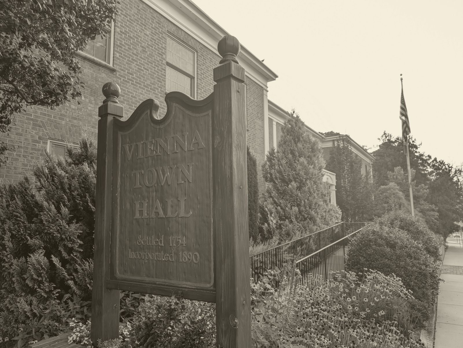 The wooden Vienna Town Hall sign, reading Settled 1754, Incorporated 1890, with the brick town hall behind